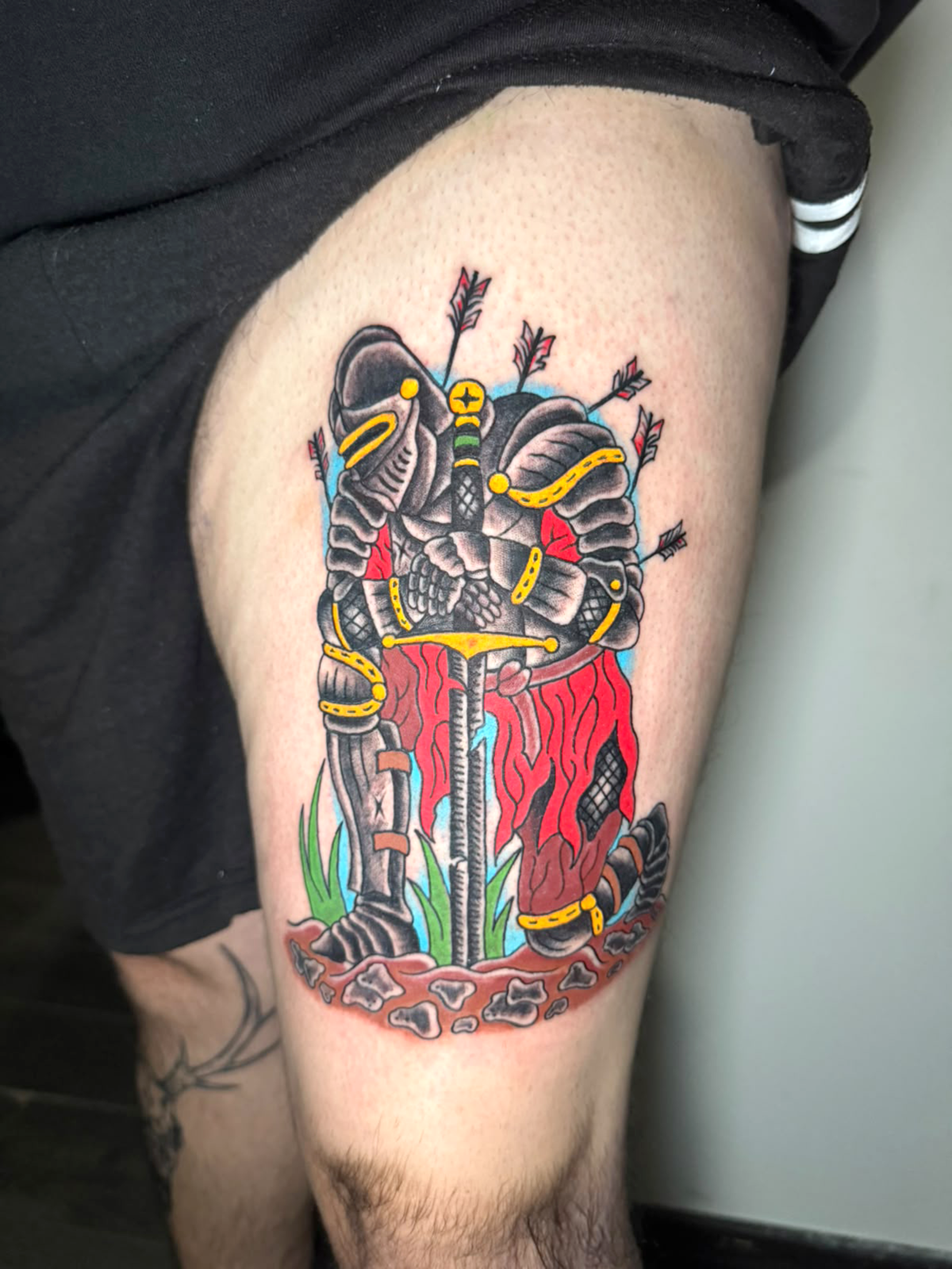 Tatuaggio a colori con un cavaliere e dettagli illustrati.