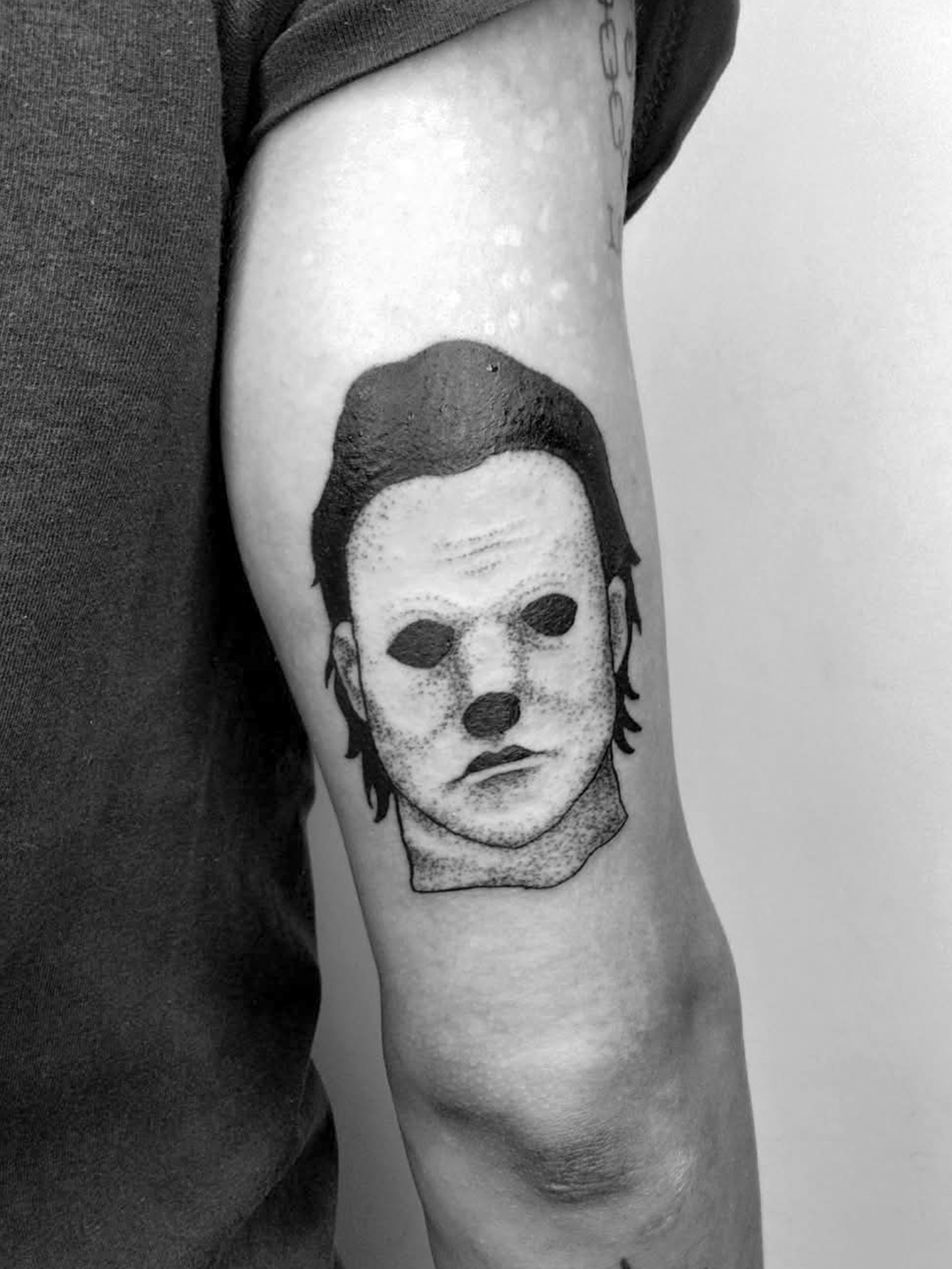 Tatuaggio in bianco e nero con un volto stilizzato.