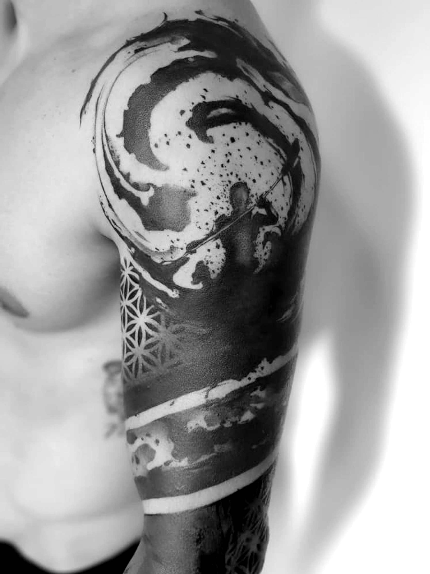 Tatuaggio geometrico e astratto in bianco e nero su spalla e braccio.